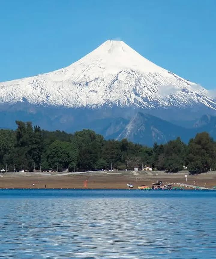 Volcán Villarrica nevado sobre la playa del lago